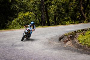 Motorcyclist navigating a sharp curve in Dhangadhi, Nepal, surrounded by lush greenery.