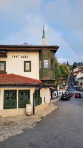 Historic Inat Kuca building with a rainbow over a quaint street in Sarajevo.